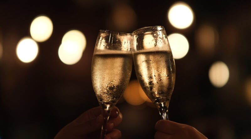 Dos manos brindando con copas en una fiesta nocturna, ilustra el cumpleaños 50 de Ángel de Brito
