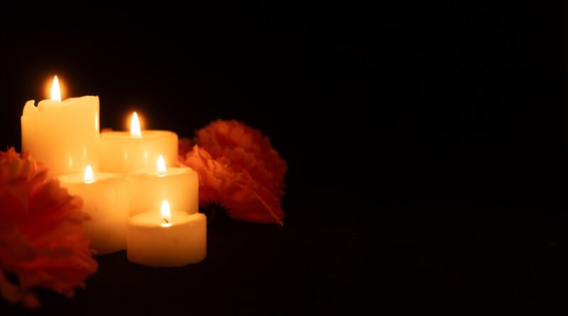 Velas encendidas entre flores que ilustran el aniversario de la AMIA y el reclamo de memoria