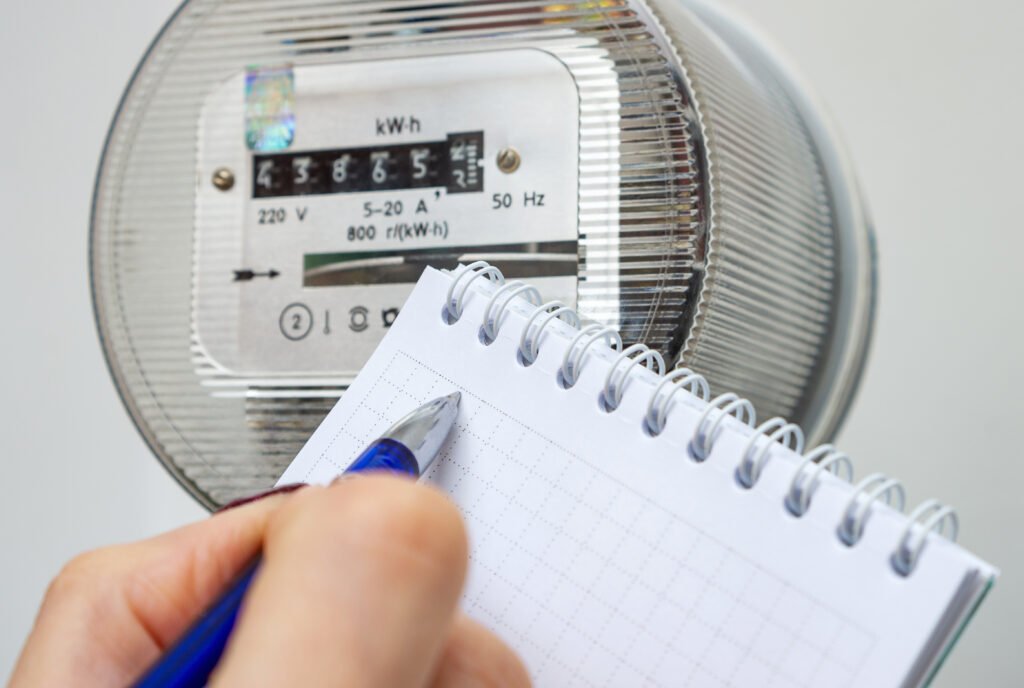 Aumentos de agosto: mano anotando la lectura de un medidor de electricidad