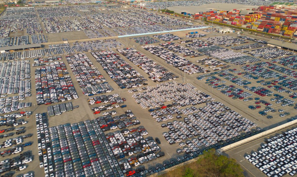 Vista aérea de autos nuevos en playón de distribución que ilustra el negocio de los autos importados