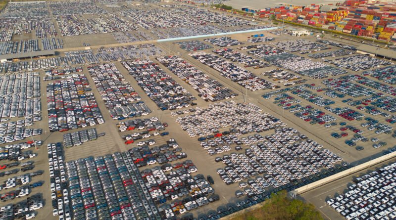 Vista aérea de autos nuevos en playón de distribución que ilustra el negocio de los autos importados