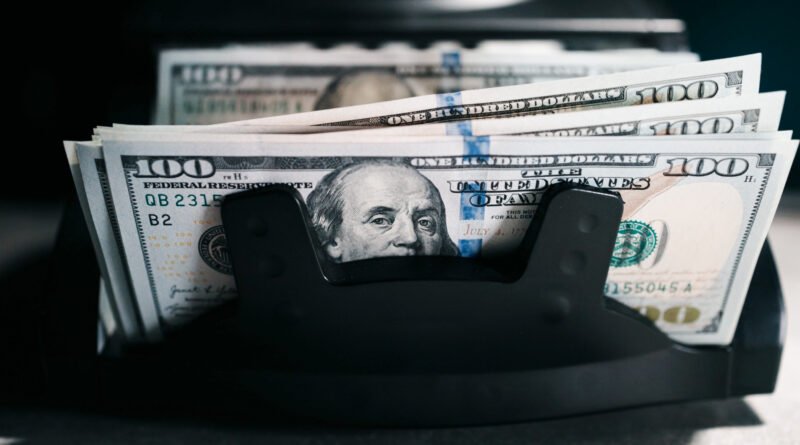 Máquina contadora de billetes de cien dólares que ilustra el dólar blue en su máximo de 2026