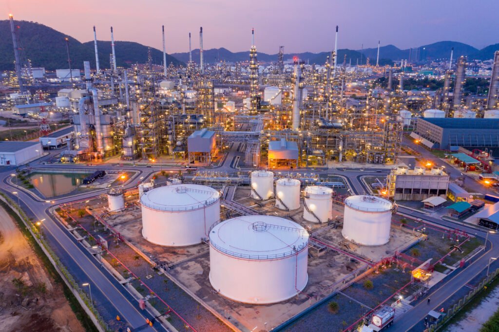 guerra en Medio Oriente: tanques de una refinería de petróleo al atardecer