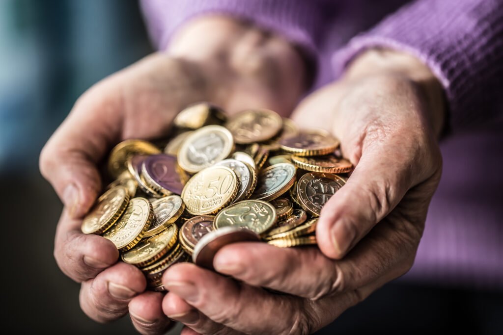 Manos de una jubilada con monedas que ilustran la jubilación mínima de julio