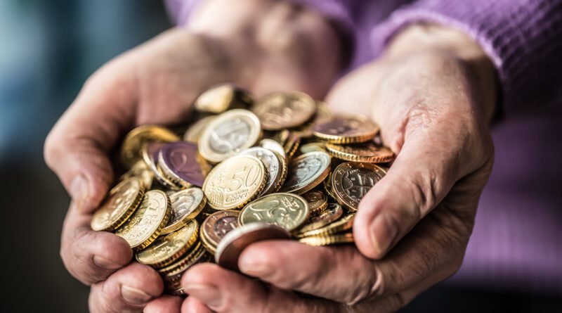 Manos de una jubilada con monedas que ilustran la jubilación mínima de julio