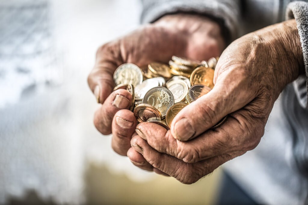 jubilaciones de agosto: manos de un jubilado sosteniendo monedas y billetes