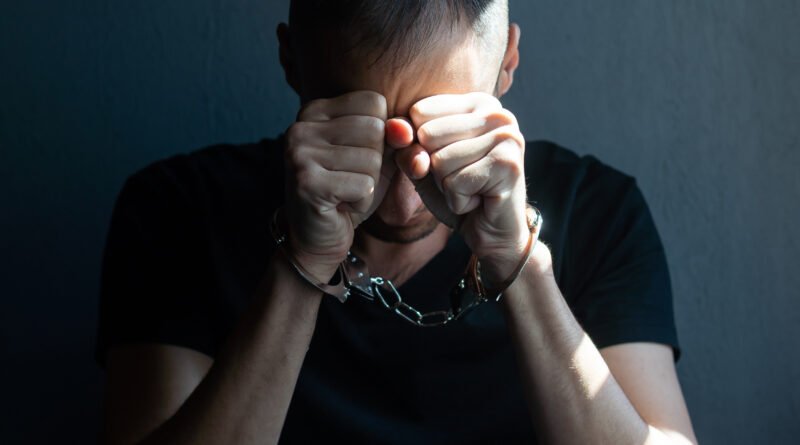 mafioso turco: manos con esposas de metal sobre fondo negro