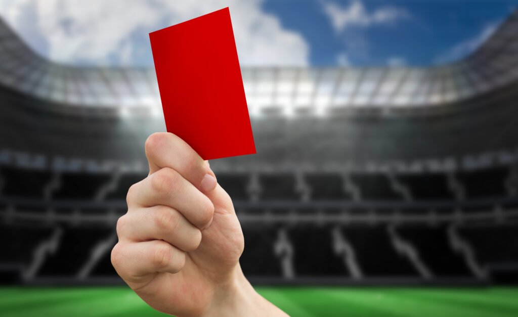 Mano mostrando una tarjeta roja en un estadio, ilustra el escándalo por los insultos racistas a Mbappé