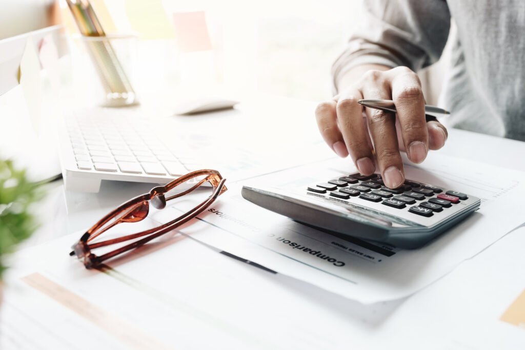 Mano con calculadora sobre informes financieros, ilustra el programa financiero que anuncia Caputo