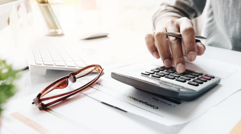 Mano con calculadora sobre informes financieros, ilustra el programa financiero que anuncia Caputo