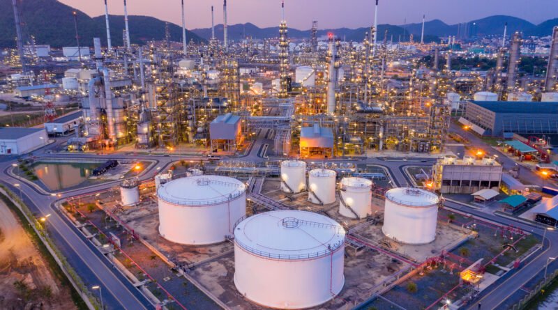 precio del petróleo: refinería y tanques de crudo al atardecer