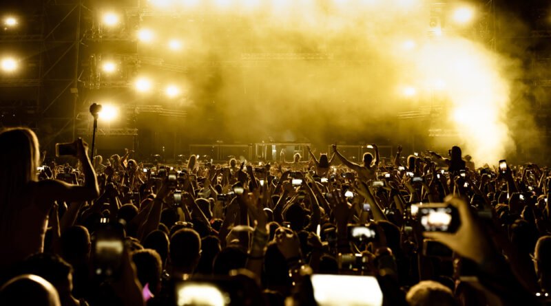 Público de espaldas con celulares frente a un escenario, ilustra los shows de Ricardo Arjona