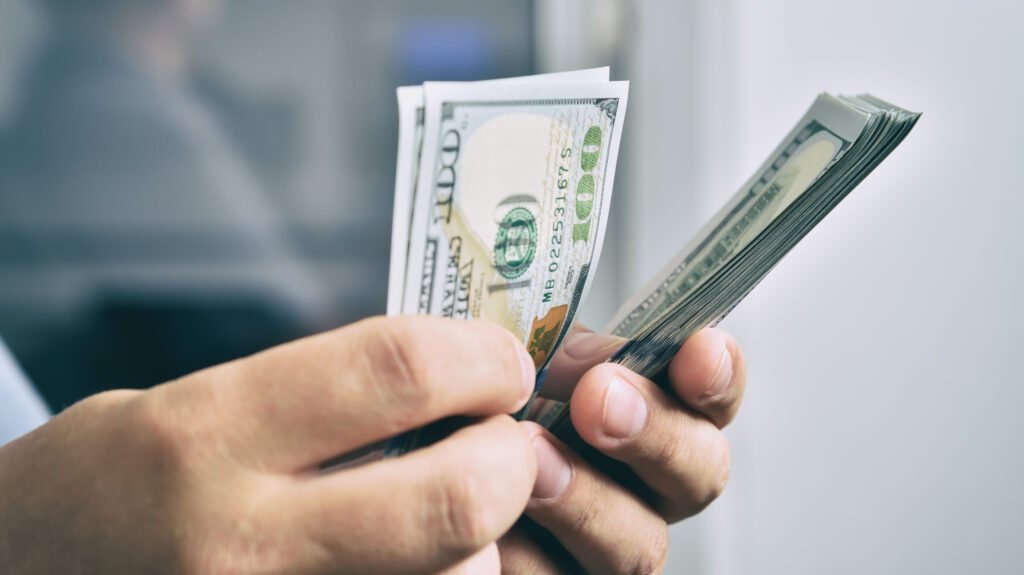Sueldos en dólares: manos contando billetes de cien dólares estadounidenses