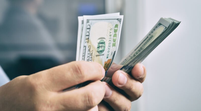 Sueldos en dólares: manos contando billetes de cien dólares estadounidenses
