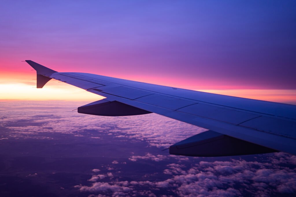 Ala de un avión en vuelo al amanecer, ilustra el turismo por el feriado del 9 de Julio