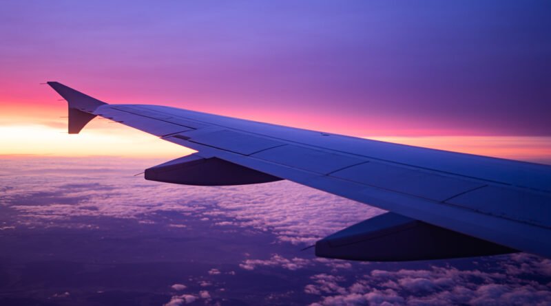 Ala de un avión en vuelo al amanecer, ilustra el turismo por el feriado del 9 de Julio