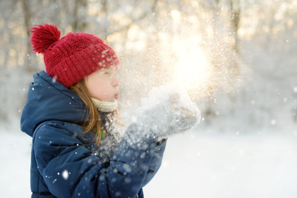 Nena abrigada divirtiéndose en un parque nevado, ilustra las vacaciones de invierno 2026