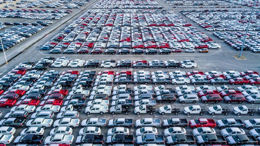 ventas de autos: vista aérea de autos 0km alineados en una playa de stock