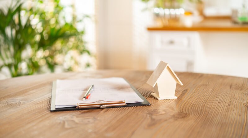 crédito hipotecario: maqueta de casa de madera y documentos en un escritorio