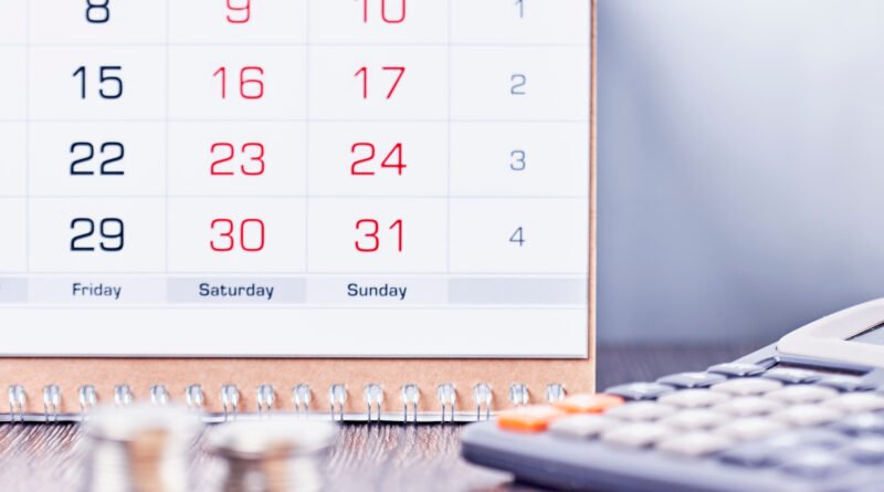 dólar a fin de año: calendario, calculadora y monedas sobre un escritorio