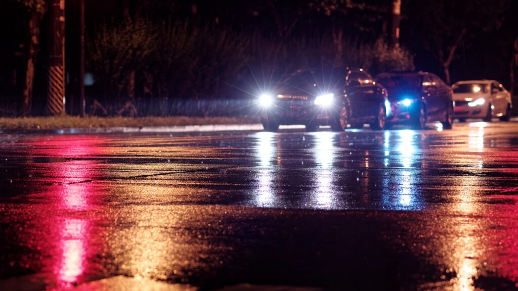 Geely Icon: autos con faros encendidos en una calle nocturna lluviosa de la ciudad