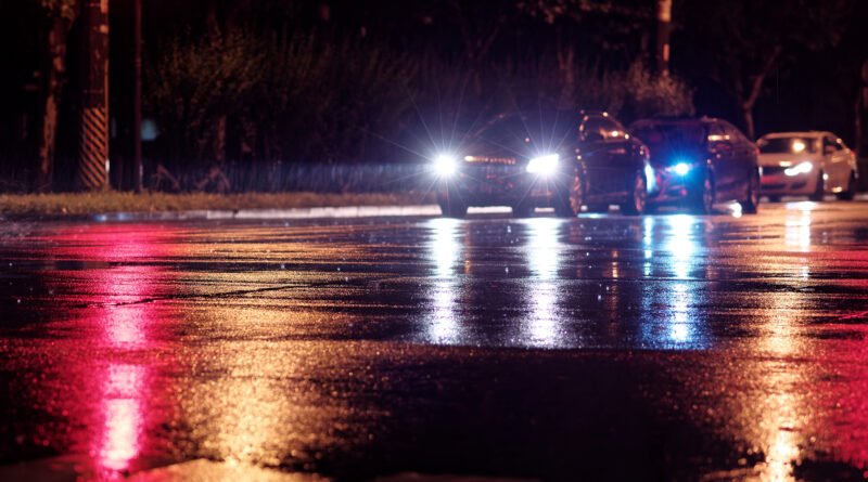 Geely Icon: autos con faros encendidos en una calle nocturna lluviosa de la ciudad