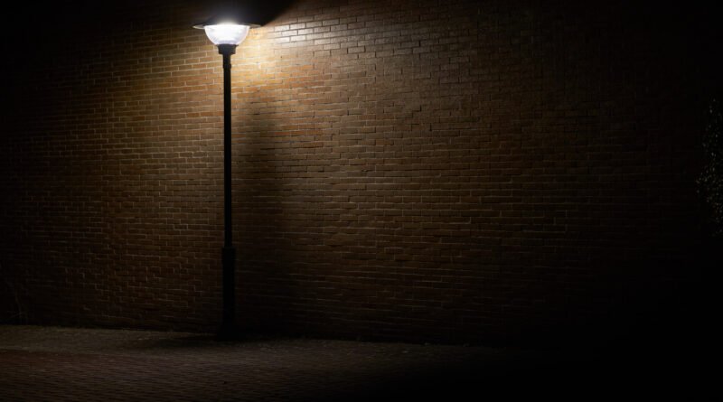 Inseguridad nocturna: farola solitaria iluminando una calle oscura de noche