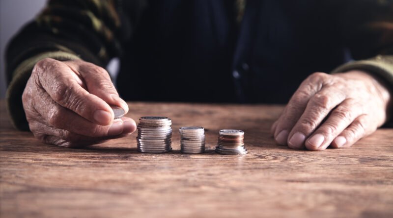 jubilación mínima: mujer mayor contando dinero sobre una mesa de madera