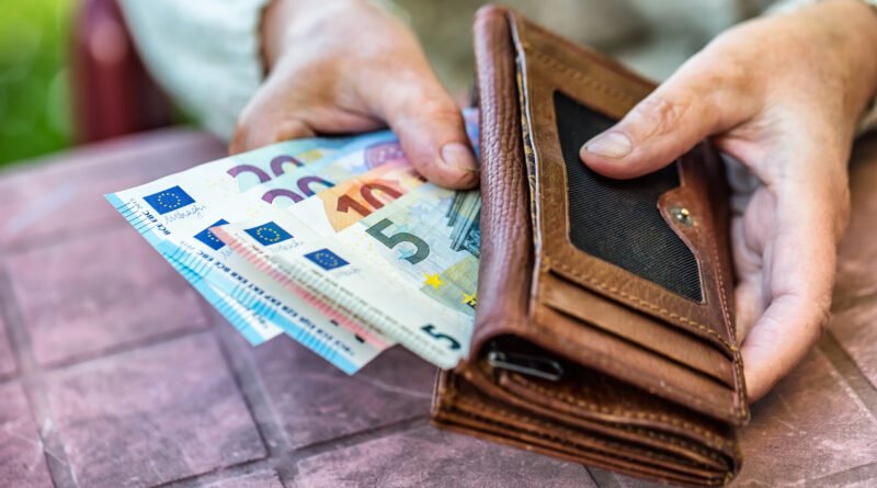 jubilaciones de agosto: una jubilada sostiene una billetera con dinero