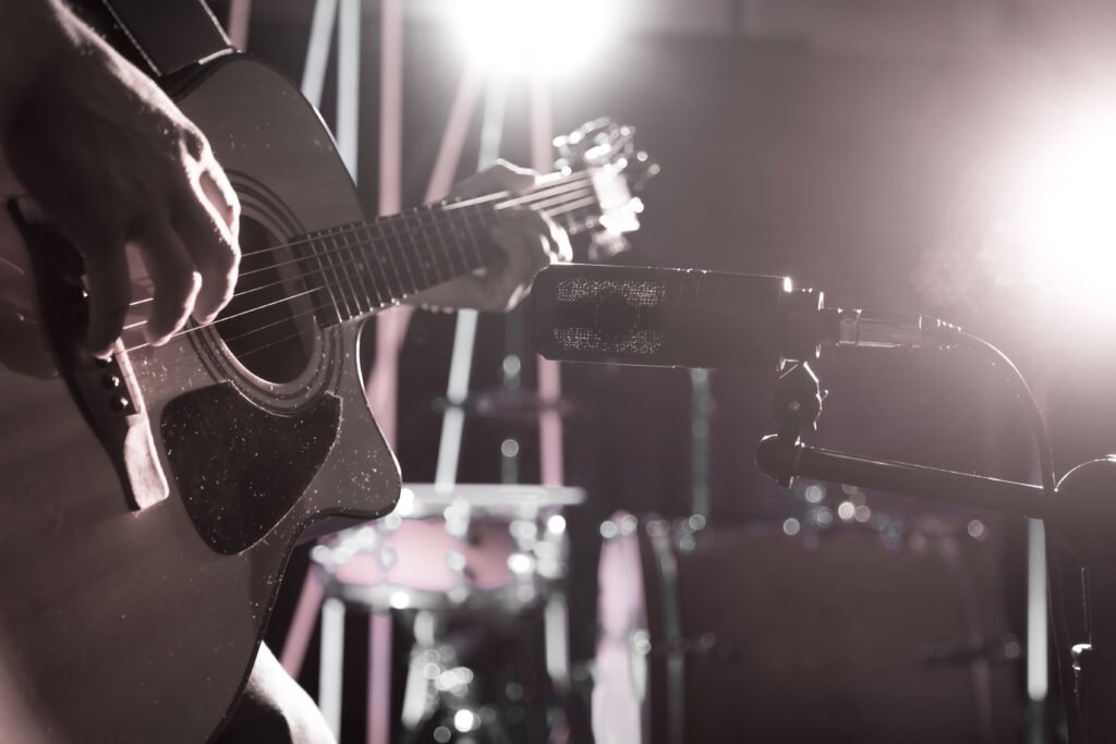 Julieta Venegas: micrófono de estudio junto a una guitarra acústica con luz cálida