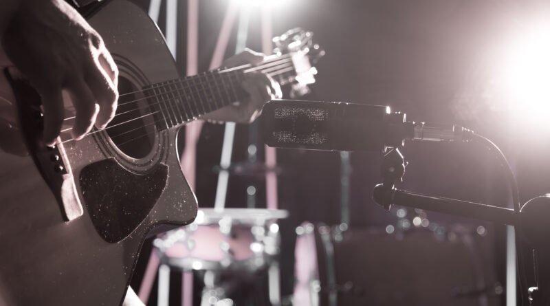Julieta Venegas: micrófono de estudio junto a una guitarra acústica con luz cálida