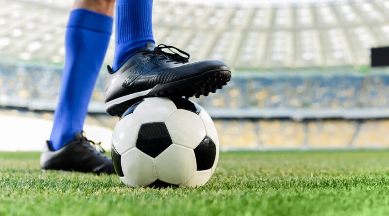 mercado de pases: botines de un futbolista junto a la pelota en el césped