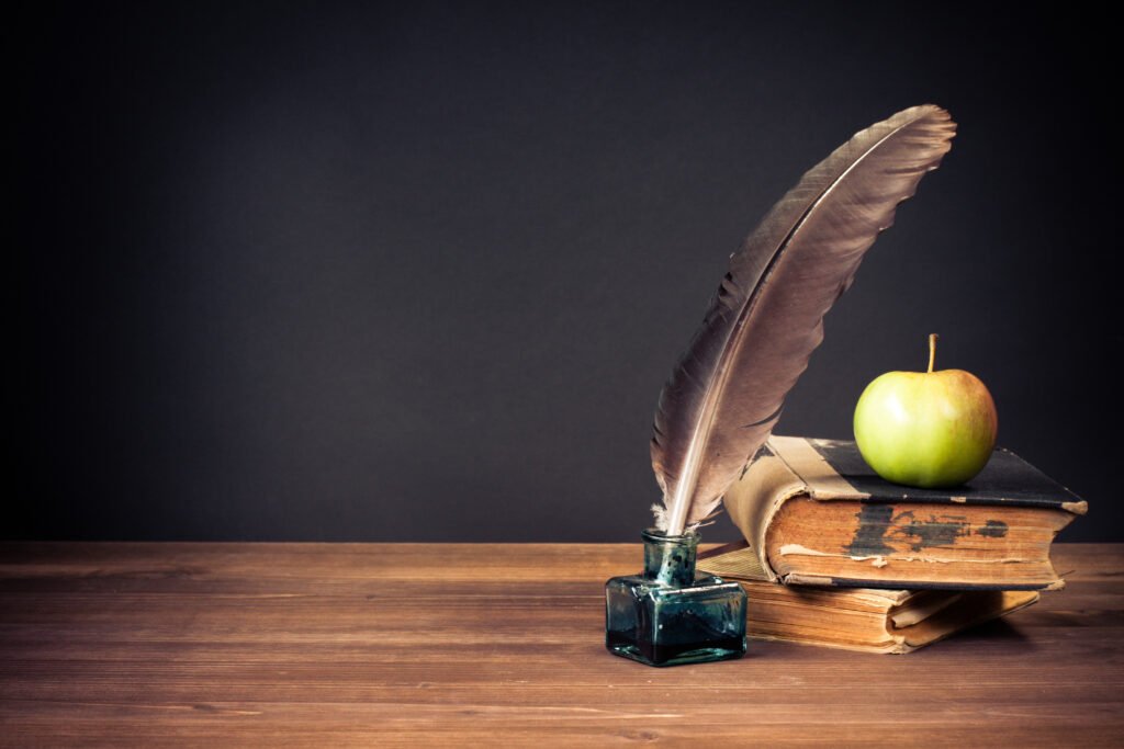 Mi brillante carrera: pluma, libros antiguos y bodegón de época sobre una mesa
