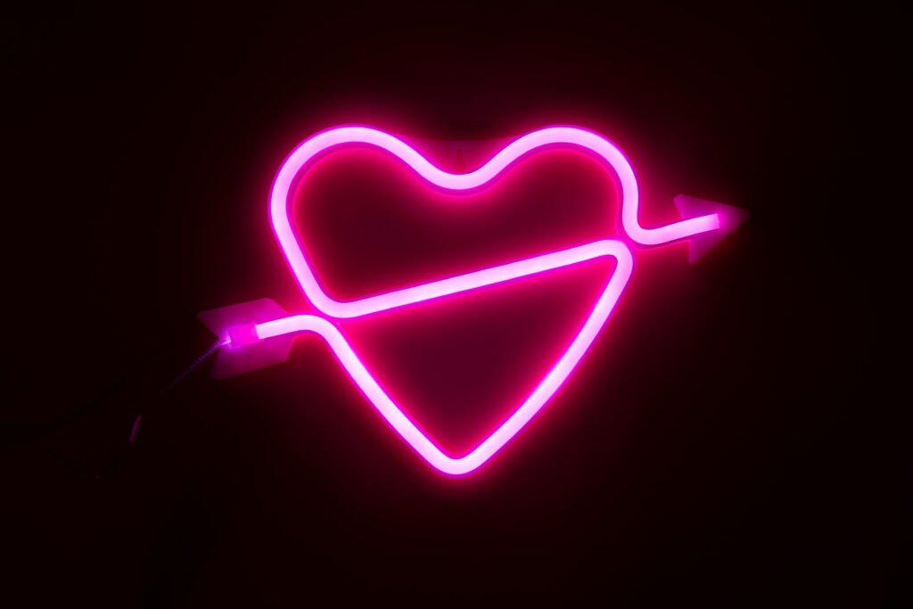 Nick Sícaro: corazón de luz neón rosa sobre fondo oscuro