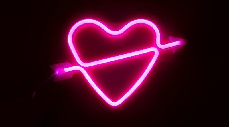 Nick Sícaro: corazón de luz neón rosa sobre fondo oscuro