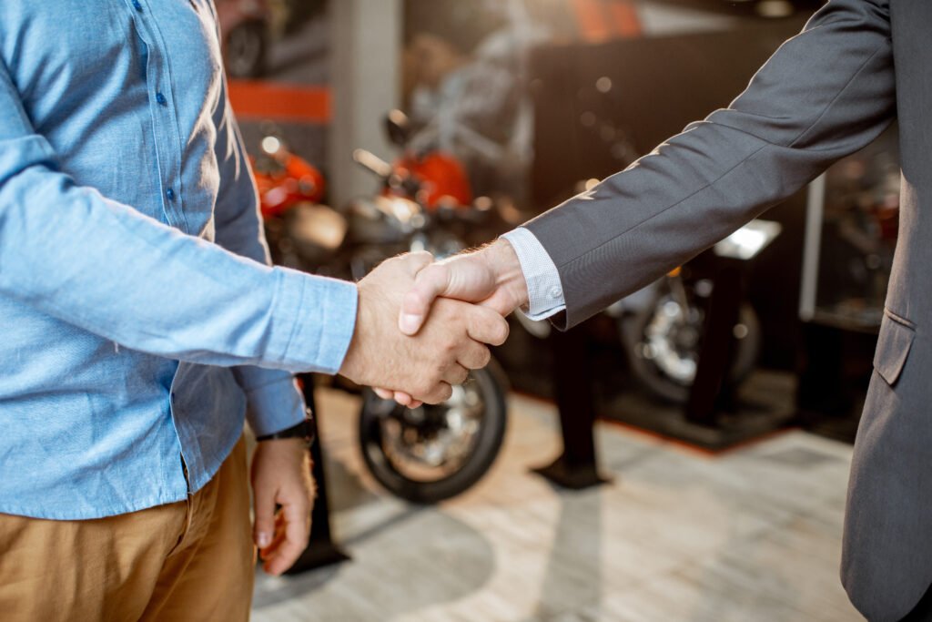plan de ahorro de motos: apretón de manos en un salón con motos nuevas