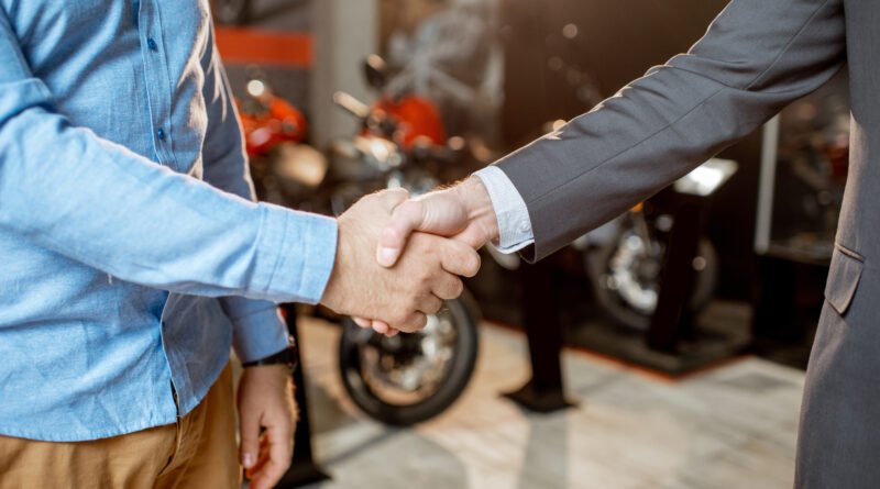 plan de ahorro de motos: apretón de manos en un salón con motos nuevas
