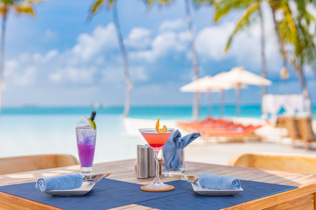 Shakira y de la Rúa: mesa con tragos frente a un mar tropical al atardecer