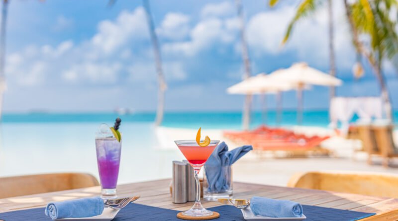 Shakira y de la Rúa: mesa con tragos frente a un mar tropical al atardecer