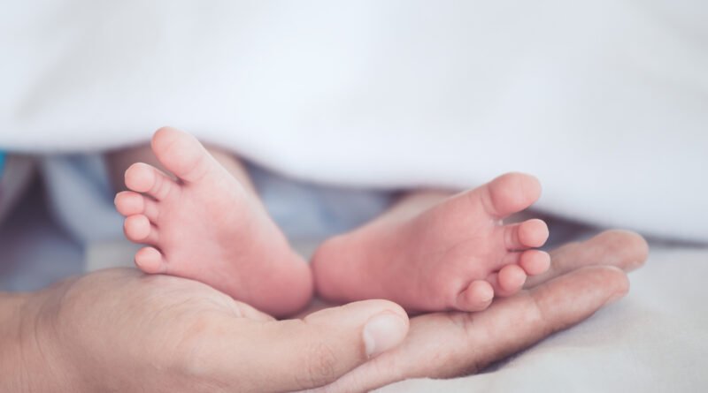Tasa de natalidad: pies de un bebé recién nacido en las manos de su madre