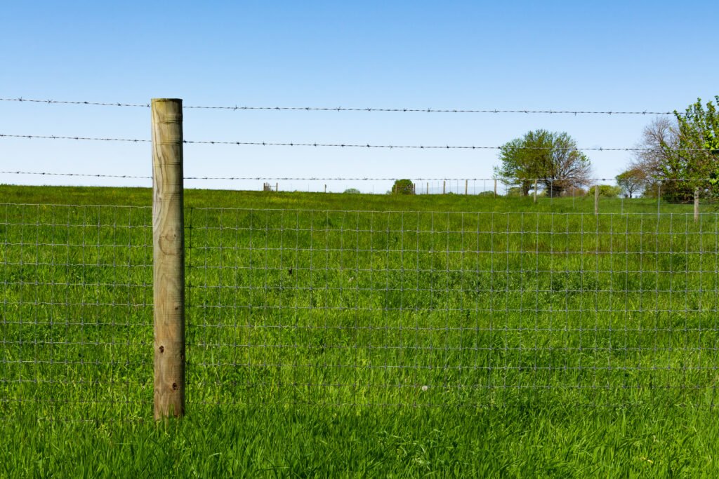 venta de tierras: poste de madera y alambrado en un campo rural