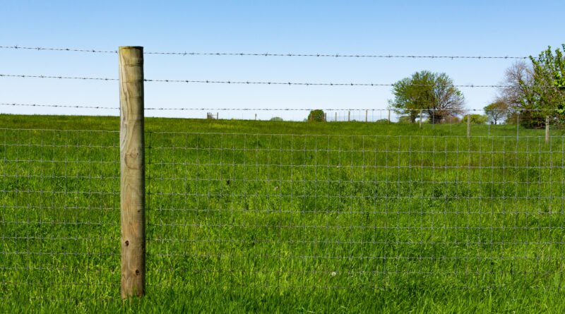 venta de tierras: poste de madera y alambrado en un campo rural