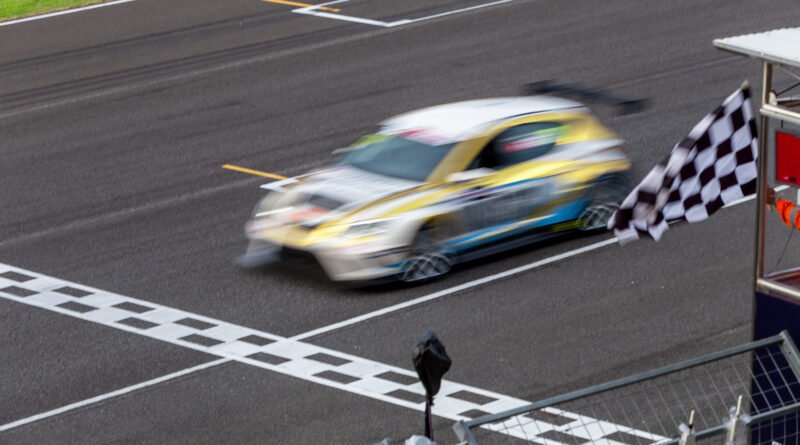 vuelta de la Fórmula 1: auto de carreras cruzando la meta con bandera a cuadros
