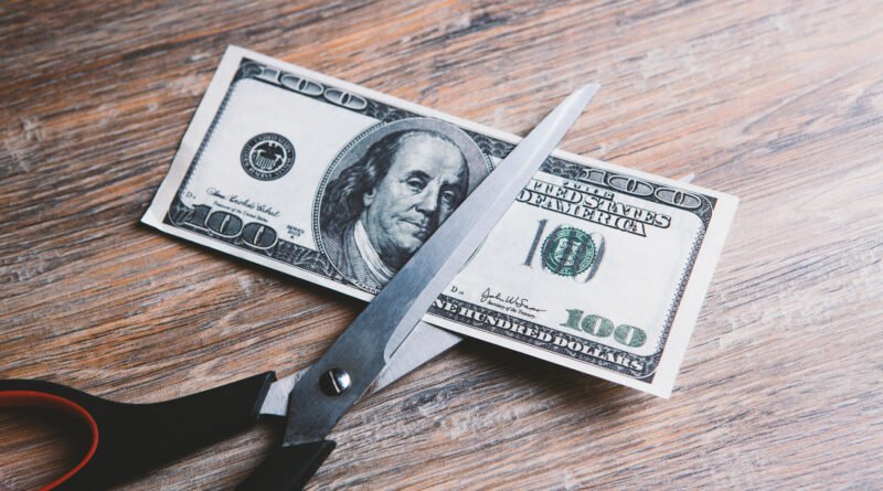 ajuste del gasto: tijera cortando un billete