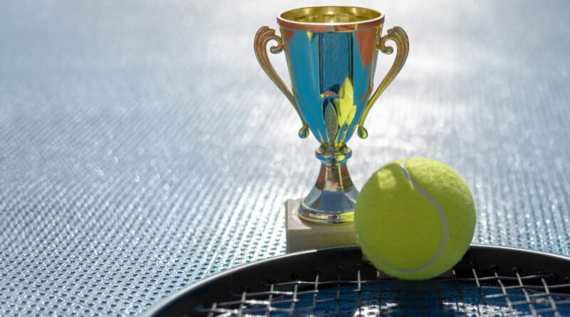 Copa Davis: trofeo dorado, pelota y raqueta de tenis a contraluz