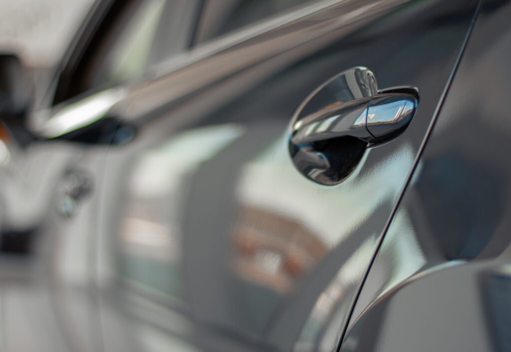 descuentos en autos: manija de la puerta de un auto gris en un salón de ventas
