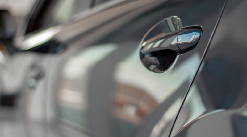 descuentos en autos: manija de la puerta de un auto gris en un salón de ventas
