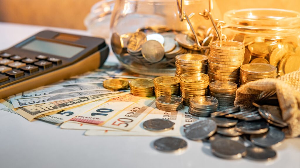 jubilaciones de octubre: calculadora, monedas y billetes sobre una mesa