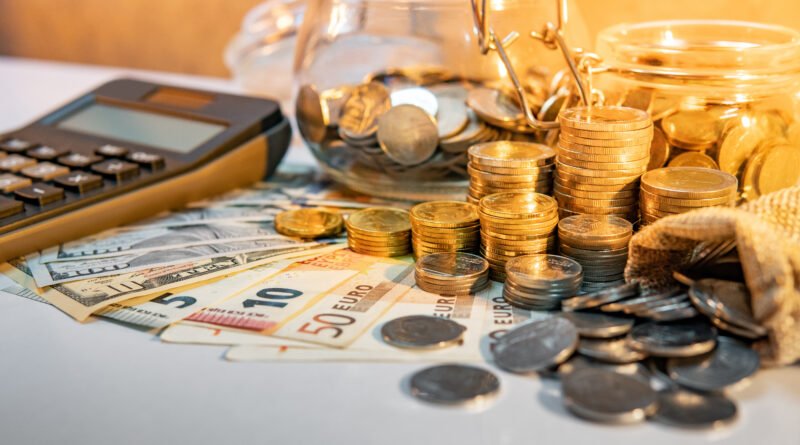 jubilaciones de octubre: calculadora, monedas y billetes sobre una mesa