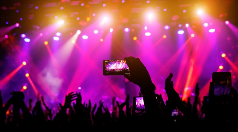 Lali en River: mano con celular grabando un recital con luces de escenario